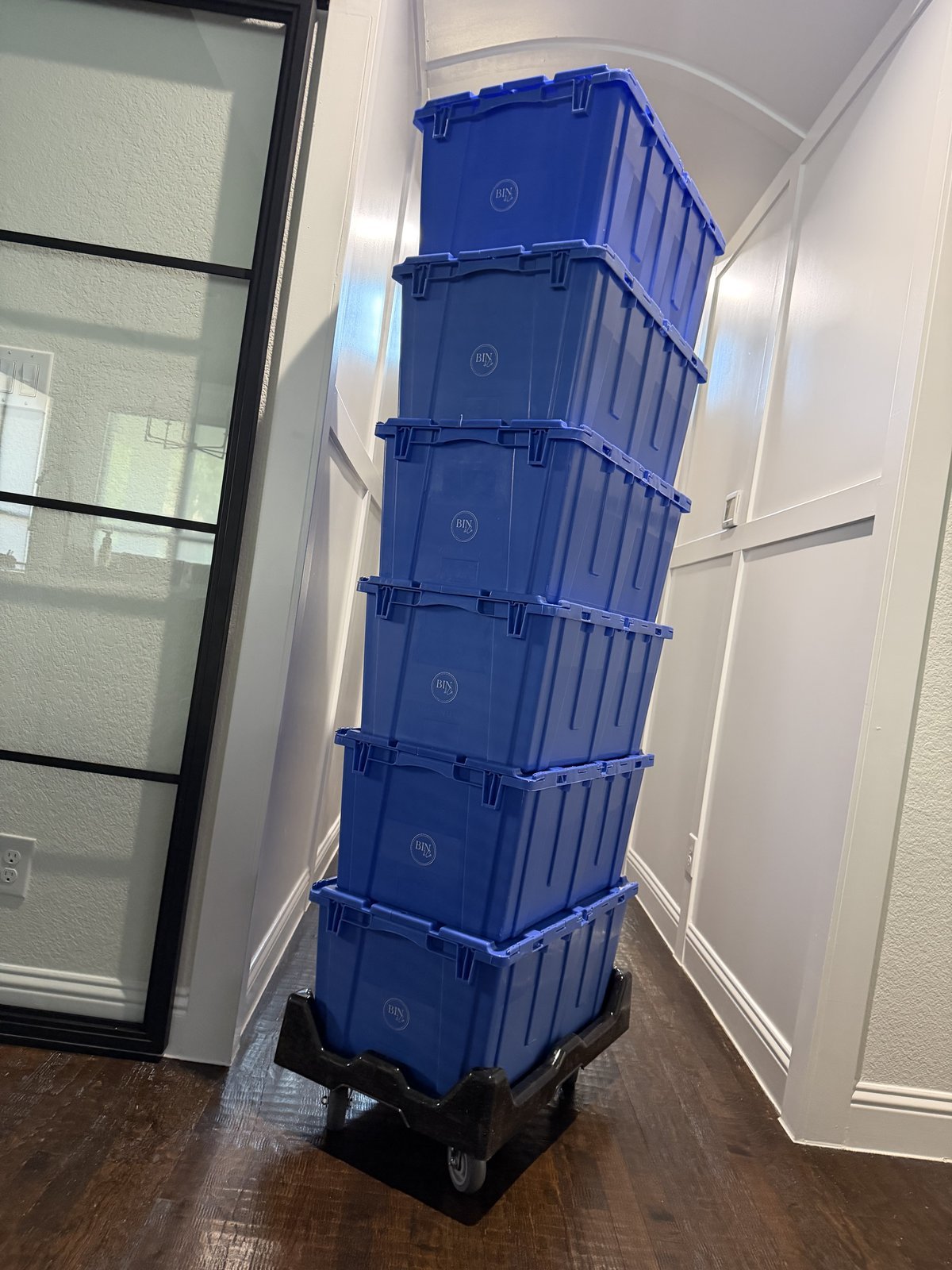 A stack of Bin & Co. attached-lid crates in a home hallway